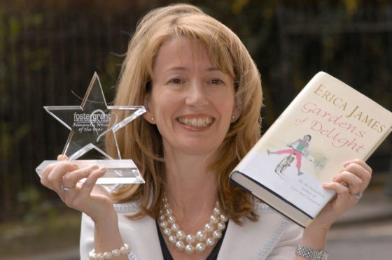 Erica James holding her novel, Gardens of Delight in one hand, and the Romantic Novelist of the Year award in the other hand.